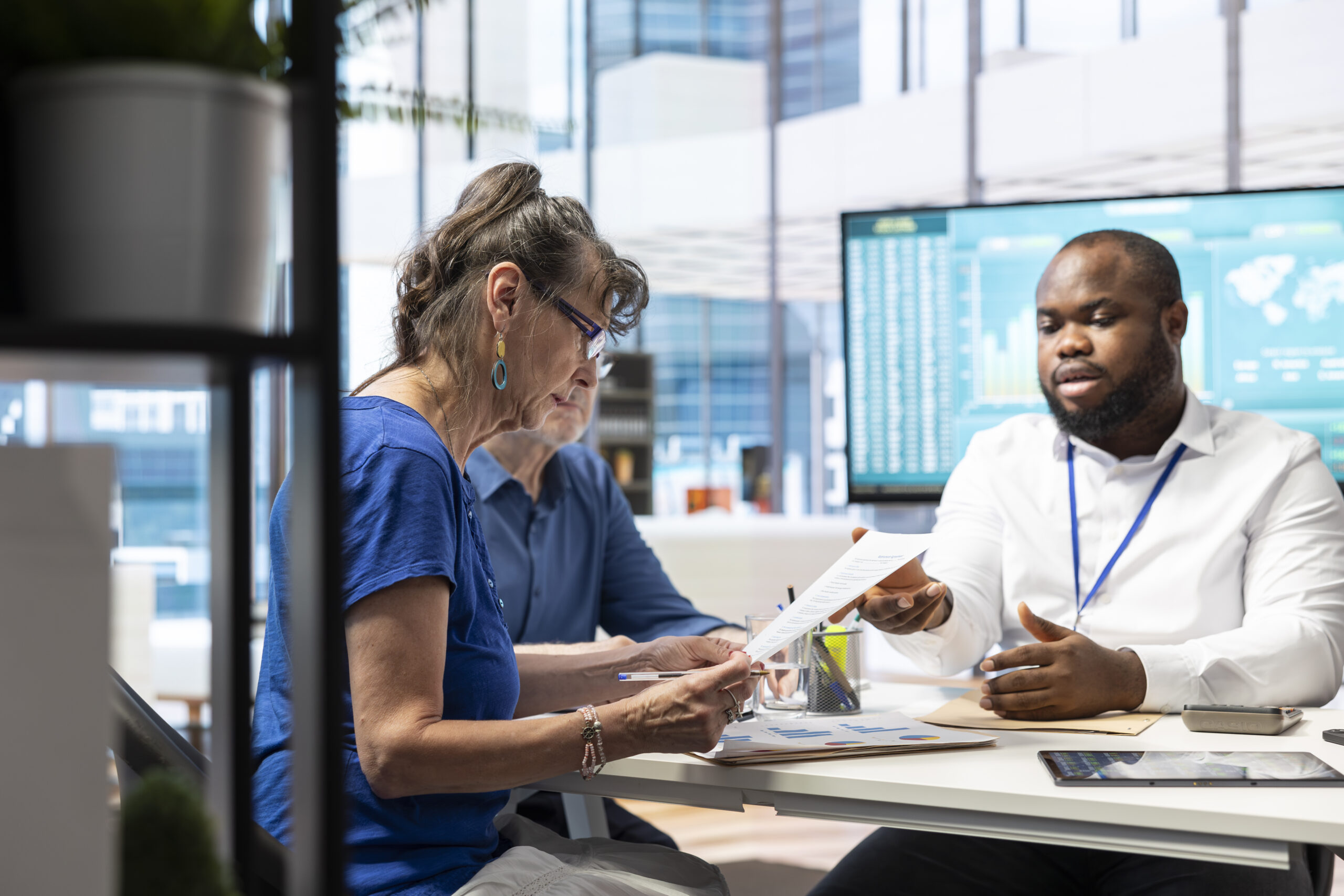 Senior person signs financial investment contract during discussion with banker it yall